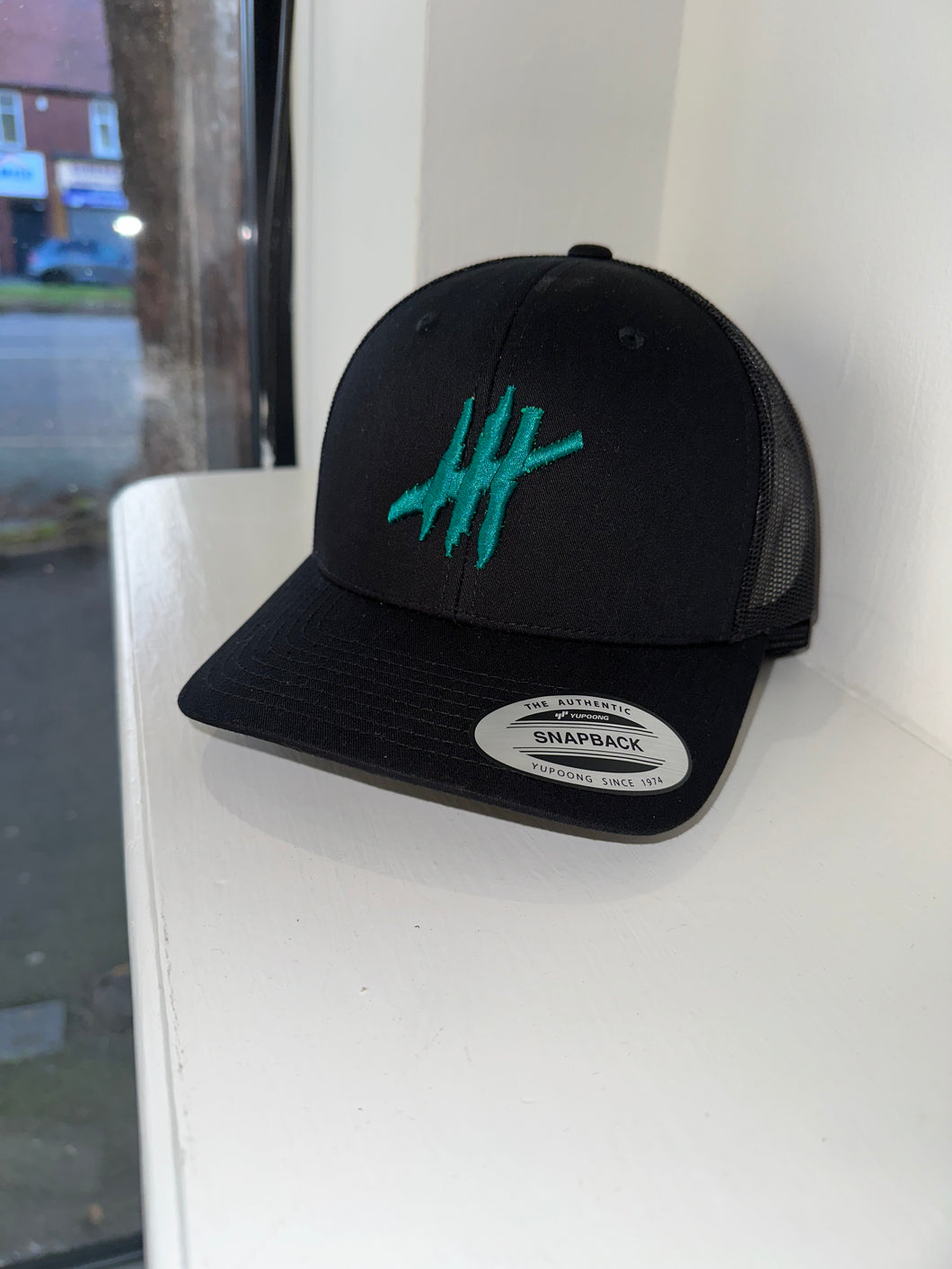 Black trucker cap with dark green logo