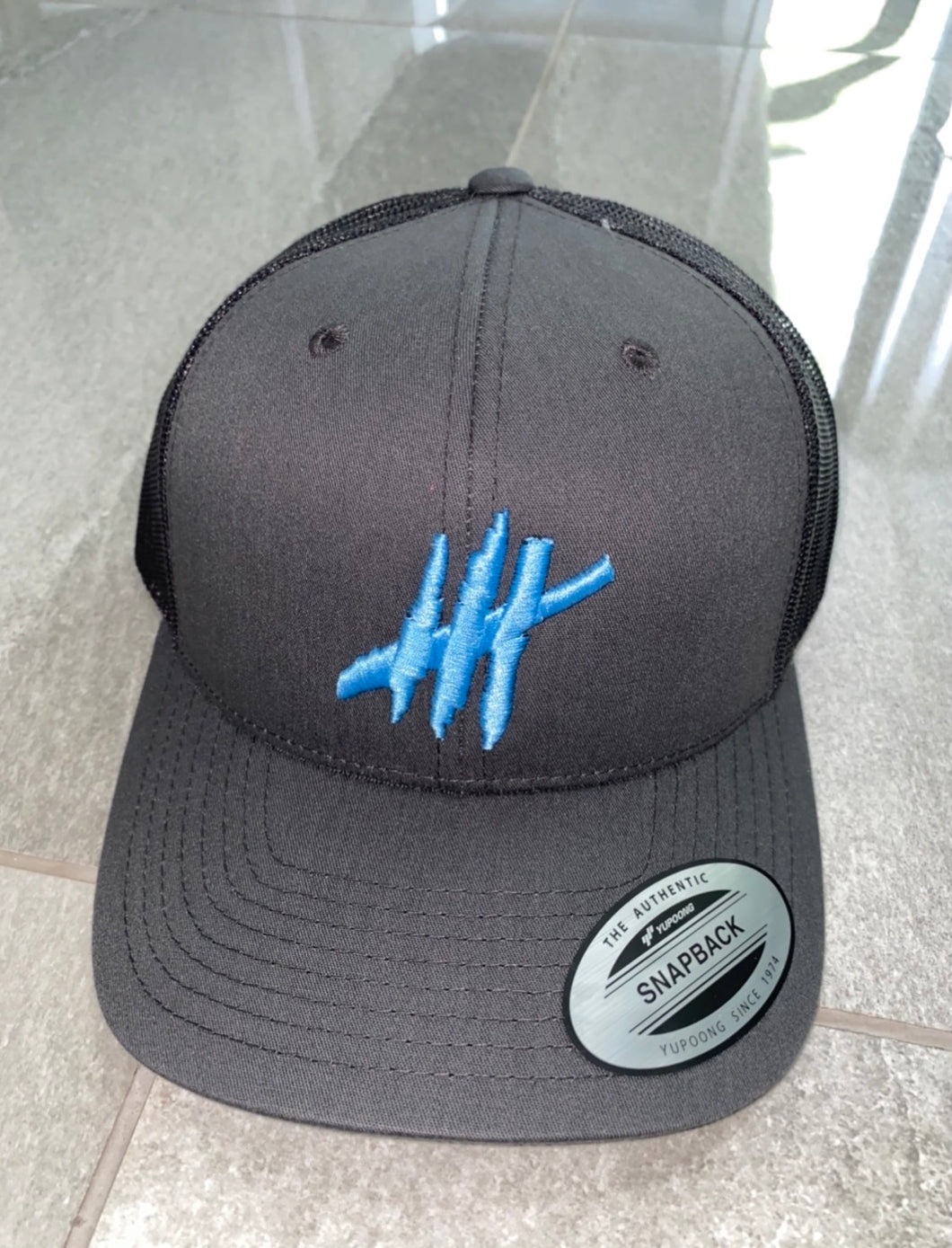 Dark grey trucker cap with light blue logo